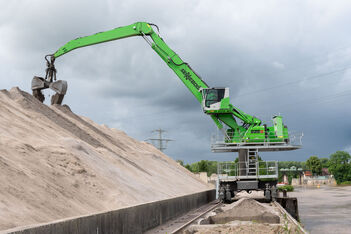 The SENNEBOGEN 835 E electric material handler with a special rail-mounted undercarriage on rails in a port.
