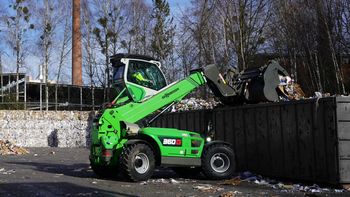SENNEBOGEN 360 G telehandler unloading recyclable material into a roll-off container at a recycling facility.