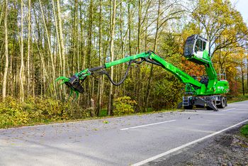 A SENNEBOGEN 718 E felling excavator safely sets down a felled tree trunk after felling.