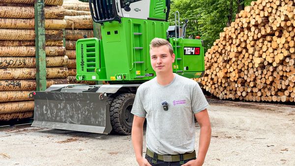 Holzhof Schmidt employees standing in front of the SENNEBOGEN 724 G in the sawmill's roundwood storage area.