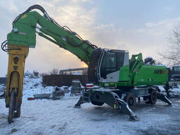 SENNEBOGEN 825 E Vario Tool mit Trevibenne CS 40RS Schrottschere bei der Bearbeitung von Metallschrott auf dem Betriebsgelände.