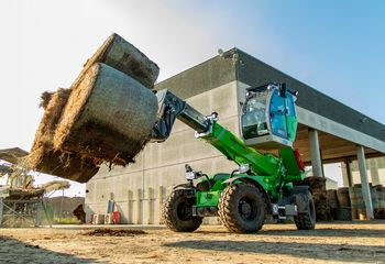 SENNEBOGEN 360 G Teleskoplader transportiert mehrere Heuballen mit einem Gabelanbau in einer Biomasseanlage.
