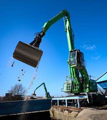 SENNEBOGEN 830 G Hybrid schwenkt mit einer sandgefüllten Schaufel beim Schüttgutumschlag im Hafen von Amsterdam.