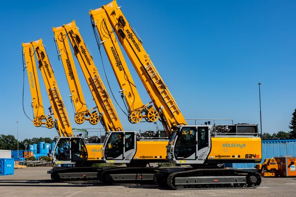 Drei SENNEBOGEN 624 E Seilbagger mit Raupenfahrwerk und aufgerichteten Auslegern auf dem Betriebsgelände von Hölscher Wasserbau.