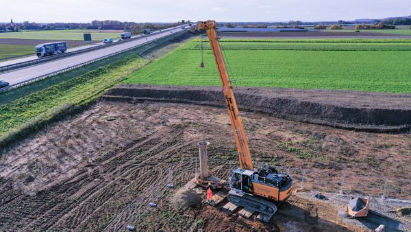 Brunnenrohre SENNEBOGEN Seilbagger von Hölscher Wasserbau beim Einsetzen eines rund 9 m langen Brunnenrohrs in ein Bohrrohr.