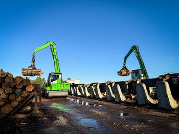 Two SENNEBOGEN 730 E pick-and-carry machines transporting logs through the aisles of a sawmill.