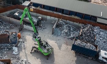 SENNEBOGEN 835 G Hybrid bewegt Metallschrott mit einem Greifer auf einem Recyclingplatz.
