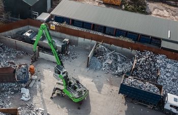 SENNEBOGEN 835 G Hybrid handling scrap metal with a grab at a recycling yard.