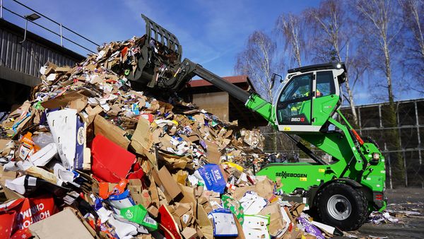SENNEBOGEN 360 G telehandler stacking recyclable material on a storage pile at a recycling facility.