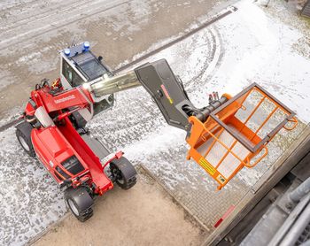 SENNEBOGEN Teleskoplader mit Arbeitskorb bei Arbeiten in der Höhe an einem Gebäude.