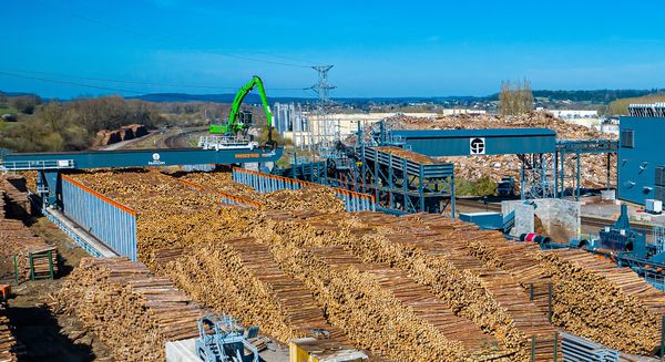 Automated round timber yard featuring a SENNEBOGEN 840 E, a HOLTEC log handler and conveyor systems to supply the sawing line.