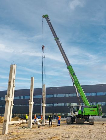 SENNEBOGEN 683 E Raupen-Teleskopkran positioniert einen Betonstützpfeiler beim Bau einer Produktionshalle.