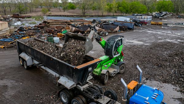SENNEBOGEN 360G mit Schaufel im Recyclingbetrieb beim Aufnehmen und Verladen von Schrottmaterial.