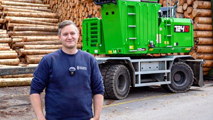 Holzhof Schmidt employees standing in front of the SENNEBOGEN 724 G in the sawmill's roundwood storage area.
