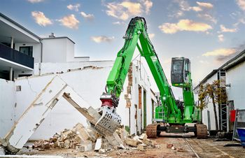 SENNEBOGEN 825 crawler excavator in demolition work on a building, using a sorting grapple to handle masonry and concrete debris.