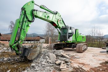 SENNEBOGEN 830 E Demolition on crawler tracks during concrete demolition, equipped with a demolition attachment and protective cab guard.