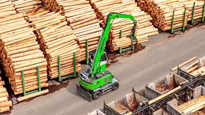 SENNEBOGEN 724 G aus der Vogelperspektive beim Beladen eines Trailers mit Rundholz im Sägewerksbetrieb. 