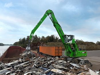 SENNEBOGEN 830 G material handler loading scrap metal directly from a cargo ship onto trucks.